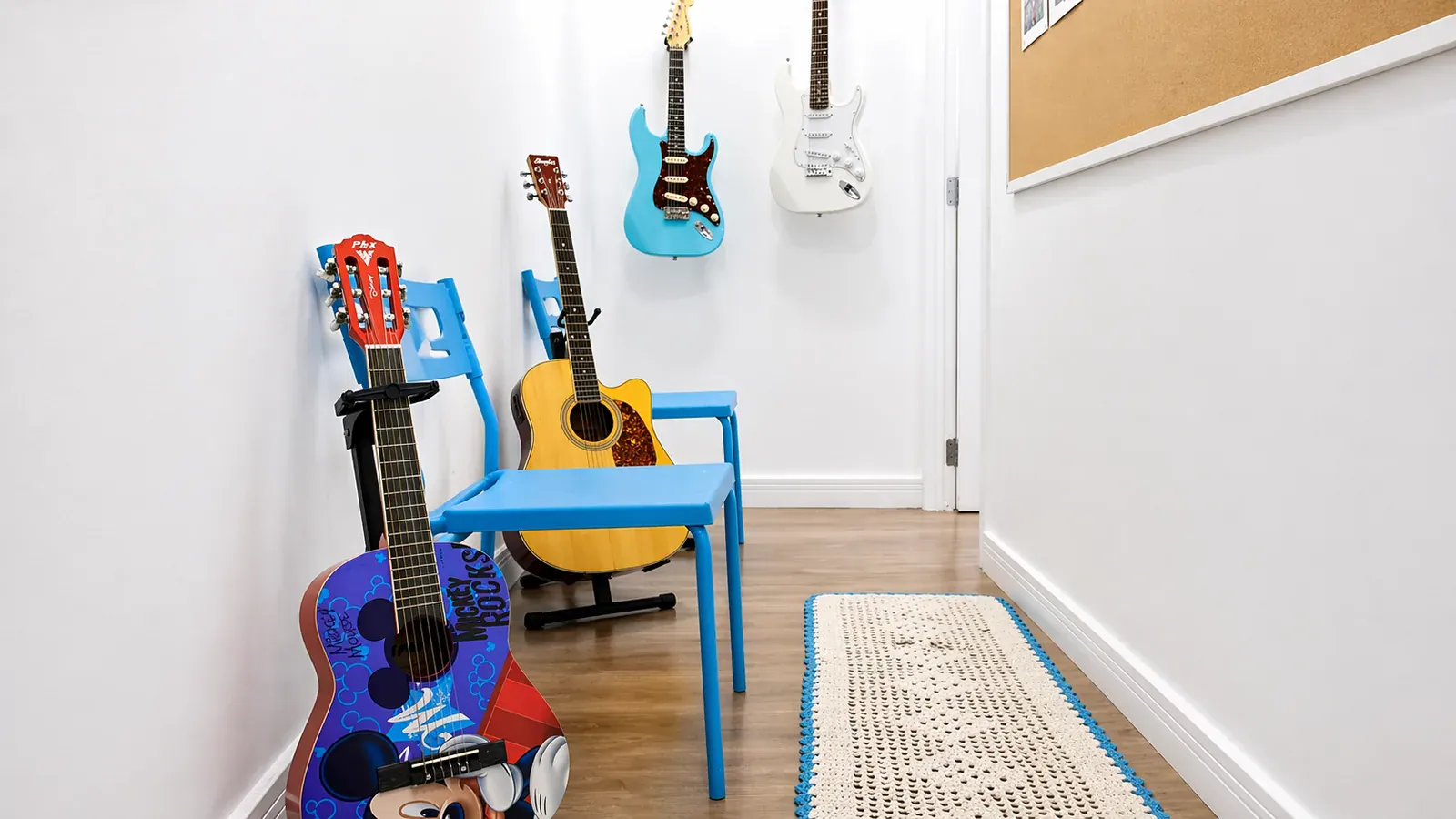 Cantinho de instrumentos com violões infantis, guitarras na parede e tapete artesanal