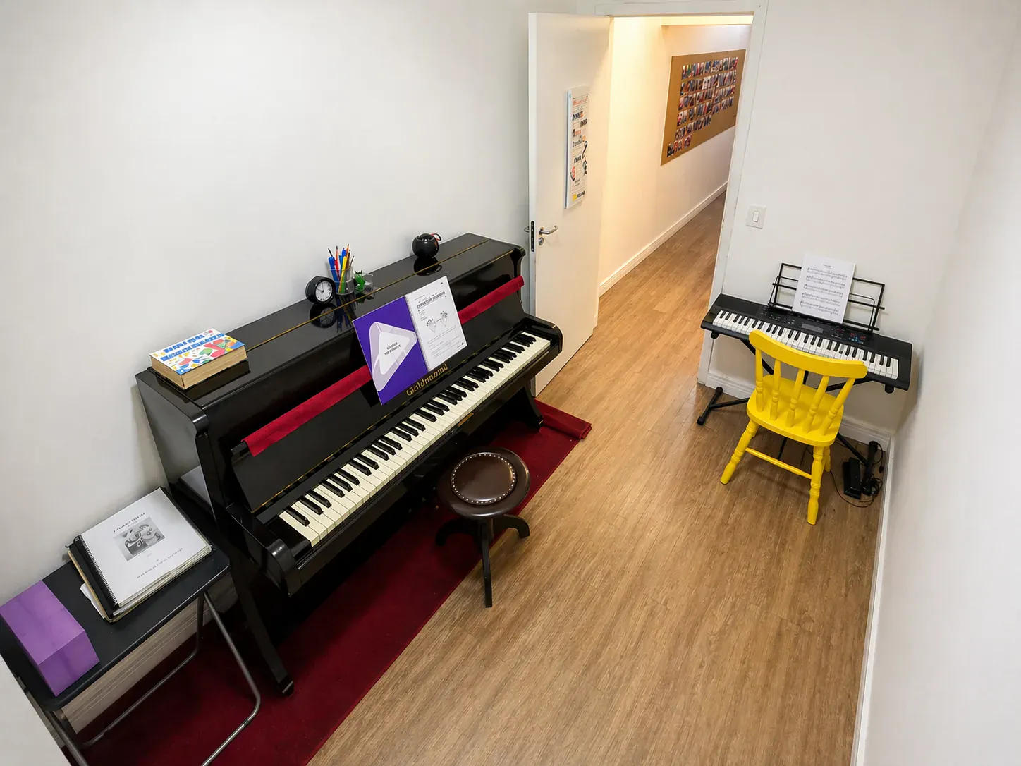 Sala de piano com piano vertical, banqueta, teclado e cadeira amarela