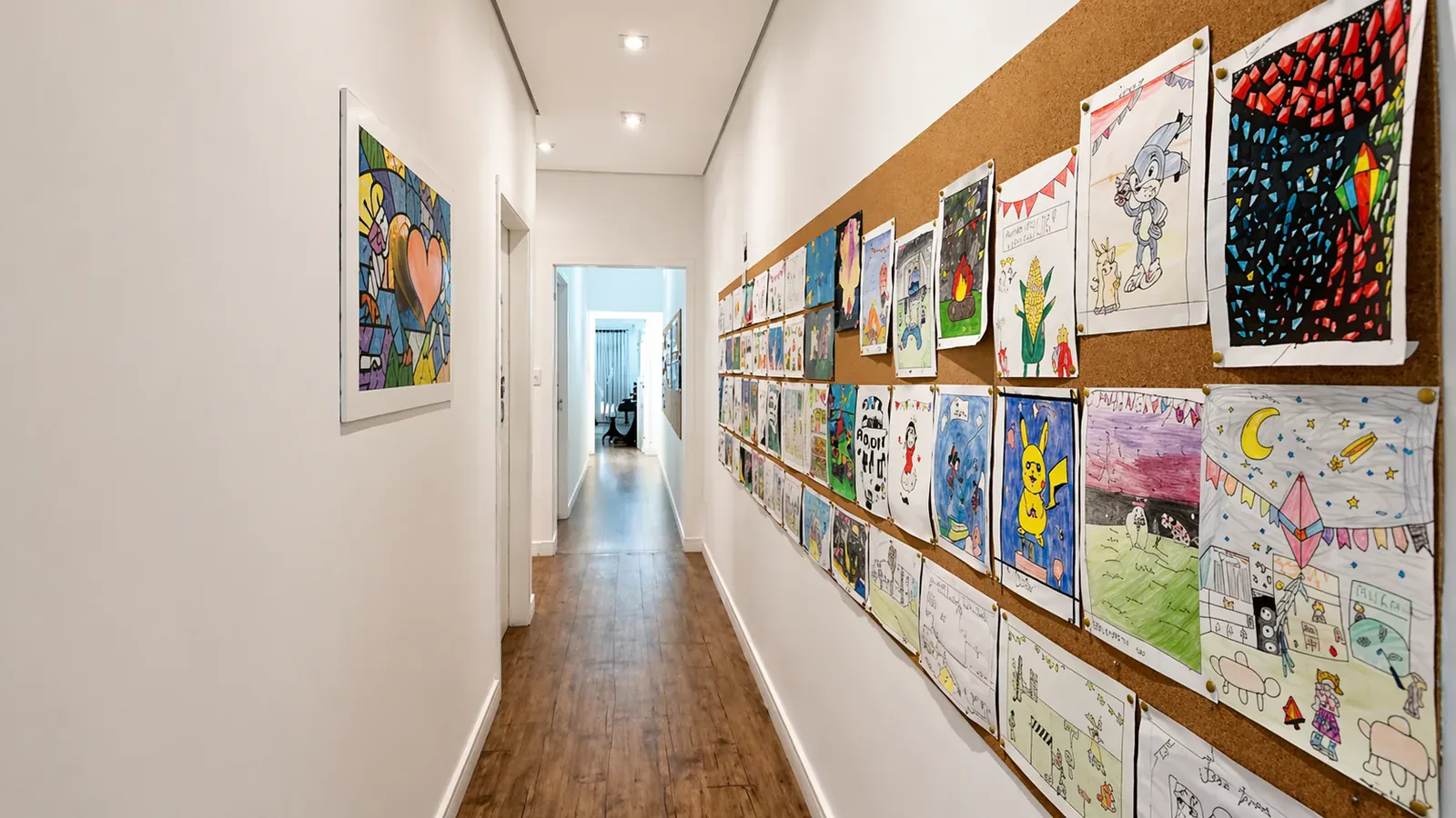 Corredor com parede de cortiça repleta de desenhos coloridos feitos pelos alunos